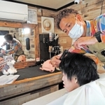 移動美容室で施術する安大陽平さん。２号車製作に向け支援を募る＝加古川市加古川町