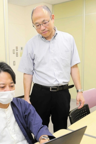 会議資料に目を通す日の出医療福祉グループの山本勝也業務執行理事（右）＝加古川市平岡町新在家