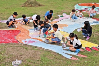 休耕田に描かれたプテラノドンの巨大絵に色を塗る子どもたち＝加古川市八幡町野村