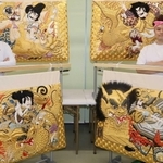 高欄掛けの新調を喜ぶ秋祭り保存会のメンバー。蘆屋道満（右上）と安倍晴明（左上）が対決する様子などが描かれている＝加古川市西神吉町岸