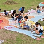 休耕田に描かれたプテラノドンの巨大絵に色を塗る子どもたち＝加古川市八幡町野村
