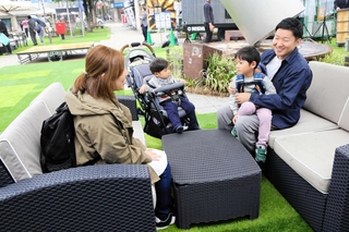 社会実験で置かれたガーデンソファーでくつろぐ家族連れら＝加古川市加古川町篠原町