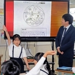 高御位山やかつめしのイラストが散りばめられた風景印の案を加古川東神吉郵便局の井上大輔局長（右）に提案する児童たち＝西神吉小学校