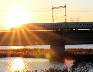 夕焼けを背景に加古川を滑るように通過する新幹線＝加古川市加古川町稲屋