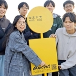 「ため池ＧＯ！」のＱＲコードが記された看板と、開発に参加する明石高専の学生たち。看板はバス停をイメージした＝稲美町加古、加古大池