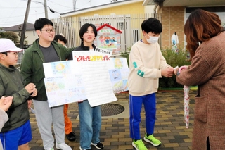 宮城県石巻市で咲いた「ど根性ひまわり」の種を配る米田小６年生＝高砂市米田町米田