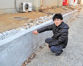 農業環境工学科の「当直」に施工管理を取り入れた石田翼さん。完成した擁壁を前に「生徒たちにコストや納期を考えながら工夫する力が身に付いている」＝県立農業高校