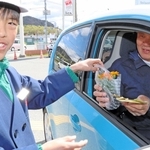 ドライバーに交通安全を訴えるメッセージと花を渡す児童＝高砂市阿弥陀町阿弥陀