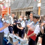 韓国の金属製食器について氷丘中２年生に説明する郭辰雄さん（左）。「日本とは使い方やマナーも違うが、それぞれに合理性がある」＝大阪コリアタウン