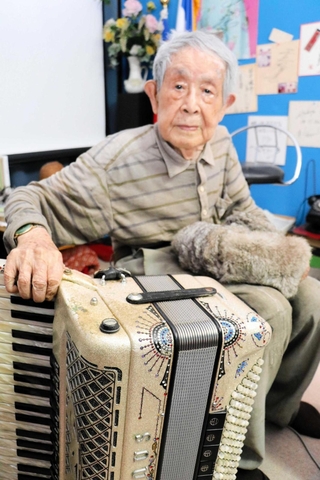 相棒のアコーディオンを見やる田中唯介さん。高齢で足がふらつき、演奏は難しくなったという＝高砂市高砂町栄町