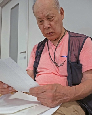 父の昇さんが戦地から家族へ宛てた手紙を読む喜多村甫さん＝稲美町役場