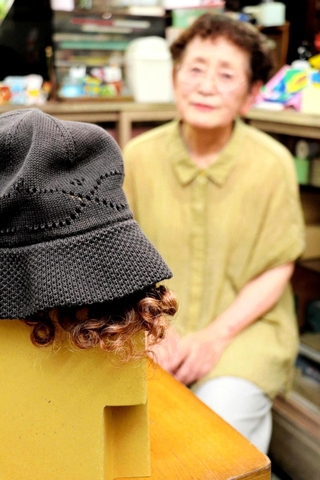 作った前髪ヘアバンドを顔に見立てた段ボールに付けてみる。「帽子をかぶせると自然でしょ」と田中さん＝加古川市加古川町寺家町