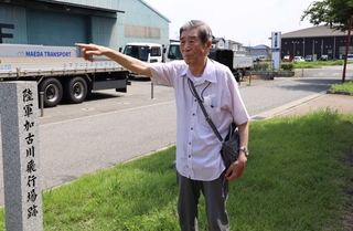 尾上公民館前の道路が戦時中は加古川飛行場の滑走路だったことを説明する上谷昭夫さん＝加古川市尾上町池田