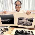 射撃訓練の様子などを収めた写真を手にする菊本睦人さん＝加古川市役所