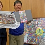 包装紙を使った商品を持つ森隆〓さん（右）と支援員の山本侑季さん。額に収まるのは森さんが城崎温泉で見た景色から着想を得た絵＝加古川市別府町新野辺　※〓は「まだれ」に「黄」