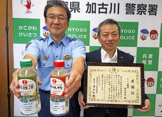 啓発メッセージを付けた調味料を配り、署長感謝状を受けたキング醸造の青木延恭取締役（右）＝加古川署