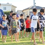 はだしで歩く感触を楽しむ子どもたちと指導した森岡亮太さん（左）＝稲美町国岡２