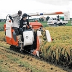 大竹宏樹さん（手前左）にコンバインの操作を教えてもらう学生＝稲美町草谷（ため池みらい研究所提供）