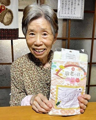 敬老の日に児童館の子どものメッセージを受け取り、喜ぶ訪問介護利用の女性＝加古川市志方町（鶴林園提供）