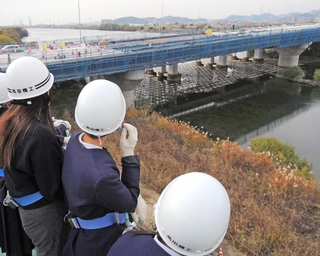 高所作業車から工事中の加古川橋を見下ろす加古川小の児童ら＝加古川市加古川町本町