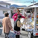 移動販売車「おまかせくん」が到着し、待ち構えた住民が買い物を始めた＝加古川市志方町西牧