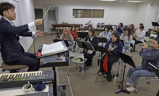 指揮者の塩山靖之さんと練習する関係者ら＝兵庫大学