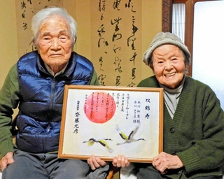 そろっての長寿を祝う「双鶴寿」と書かれた兵庫県からの祝い状を手にする本川和雄さん、きさゑさん＝稲美町中一色