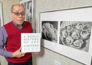 自身が取り上げられた世界を代表する芸術家の国際書籍を手にする鉛筆画家、坂本七海男さん＝加古川市東神吉町西井ノ口
