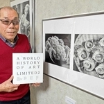 自身が取り上げられた世界を代表する芸術家の国際書籍を手にする鉛筆画家、坂本七海男さん＝加古川市東神吉町西井ノ口