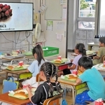 給食で稲美町産のブドウを食べながら、生産者を紹介する動画を見る子どもたち（天満東小提供）
