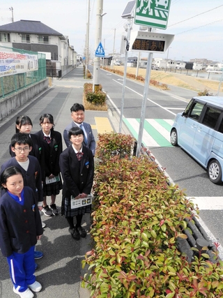 横断者サポート表示板と子ども議会で対策を求めた井口聡実さん（右手前）や播磨南小と播磨南中の児童、生徒ら＝播磨町古宮５