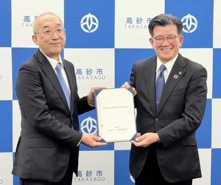 「高砂市民病院の管理に関する基本協定書」を手にする都倉達殊市長と地域医療振興協会の藤来靖士理事長（左）＝高砂市役所