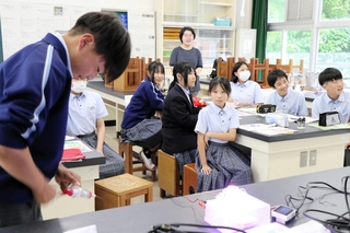 手回し発電機でどれだけ発電できるか挑戦する生徒＝加古川市志方町志方町