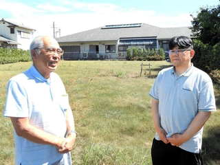 グループホームの建設予定地で計画について話すこばと会の鳴瀬敏雄理事長（左）とこばと園の岡本晃幸施設長。奥は園舎＝稲美町野寺