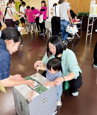 実際の選挙で使われる投票箱に模擬投票する親子連れ＝高砂市高砂町松波町