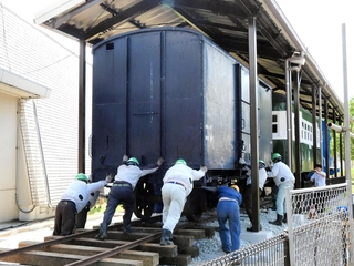 旧別府鉄道の貨車を押し進める作業員たち＝播磨町大中１