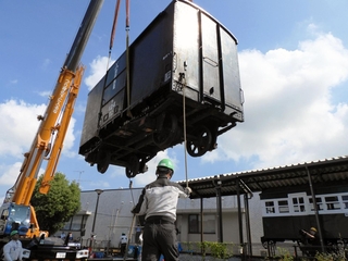 クレーン車でつり上げられる旧別府鉄道の貨車。右奥は展示施設の客車＝播磨町大中１