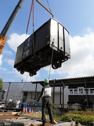 クレーン車でつり上げられる旧別府鉄道の貨車。右奥は展示施設の客車＝播磨町大中１