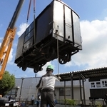 クレーン車でつり上げられる旧別府鉄道の貨車。右奥は展示施設の客車＝播磨町大中１