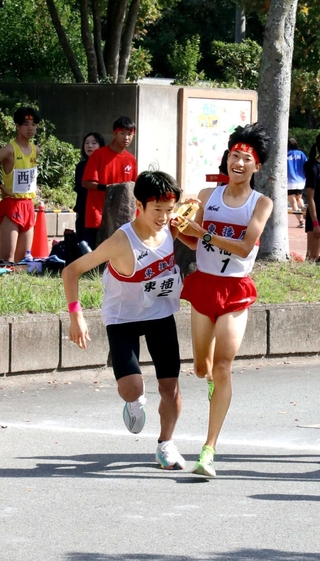 男子・東播磨１区の二村直樹選手（右）からたすきを受ける２区の橋本宏輝選手＝西脇市西脇