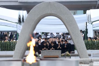 　米軍の原爆投下から８０年の「原爆の日」となり、慰霊碑に手を合わせる人たち＝６日午前５時３６分、広島市中区の平和記念公園