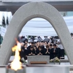　米軍の原爆投下から８０年の「原爆の日」となり、慰霊碑に手を合わせる人たち＝６日午前５時３６分、広島市中区の平和記念公園