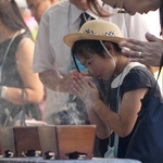 　終戦の日を迎え、千鳥ケ淵戦没者墓苑で手を合わせる子ども＝１５日午前９時２４分、東京都千代田区