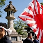 　１５日、靖国神社（東京・九段北）で旭日旗を掲げる人。（ロイター＝共同）