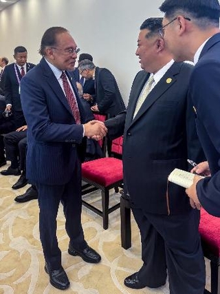 　マレーシアのアンワル首相（左）と握手を交わす北朝鮮の金正恩朝鮮労働党総書記＝３日、北京（アンワル氏のフェイスブックから、共同）