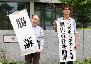　控訴審判決を受け、「勝訴」などと書かれた紙を掲げる原告側弁護士ら＝１１日午後、福岡高裁前