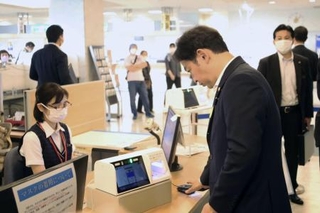 　スマホ保険証を使った受け付けを体験する福岡厚労相（手前右）＝７月、東京都目黒区の東京医療センター