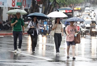 　台風１８号の影響で雨が降る中、歩く人たち＝２３日、台北（ＡＰ＝共同）