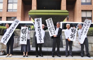 　三重県４市の生活保護減額訴訟の控訴審判決後、「勝訴」などと書かれた垂れ幕を掲げる原告団の弁護士ら＝２６日午後、名古屋高裁前