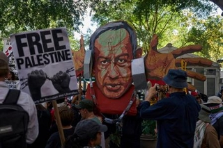 　イスラエルのネタニヤフ首相の似顔絵を掲げ、抗議する人たち＝２６日、ニューヨーク（ロイター＝共同）